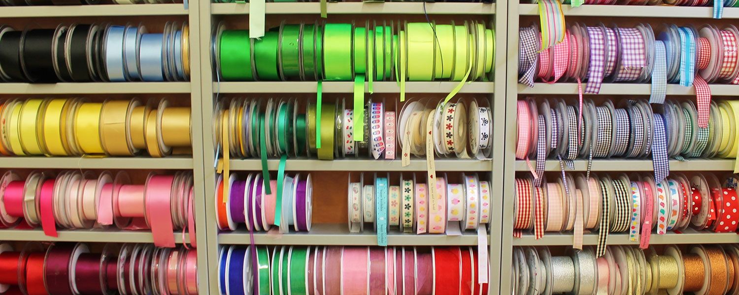 Fabrics, haberdashery, knitting and sewing shops insurance: A shelf featuring rolls of ribbons.