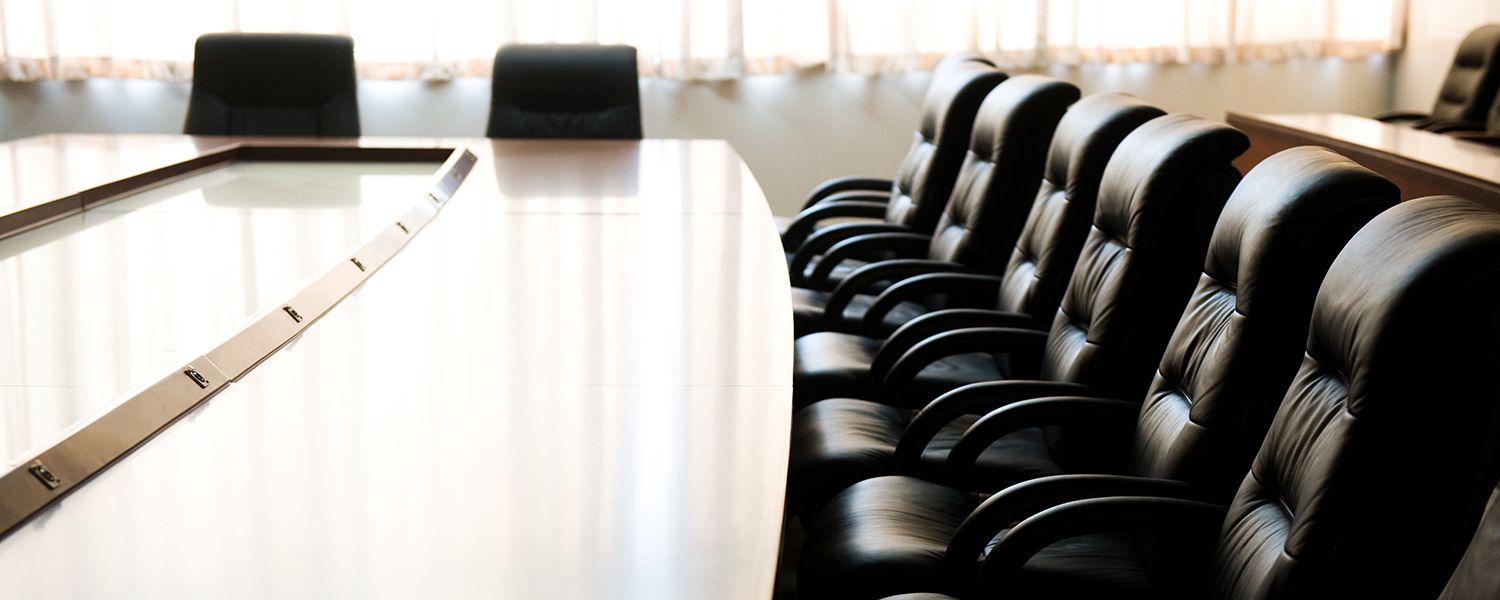 Directors and Officers: Empty row of black chairs at a conference table. 