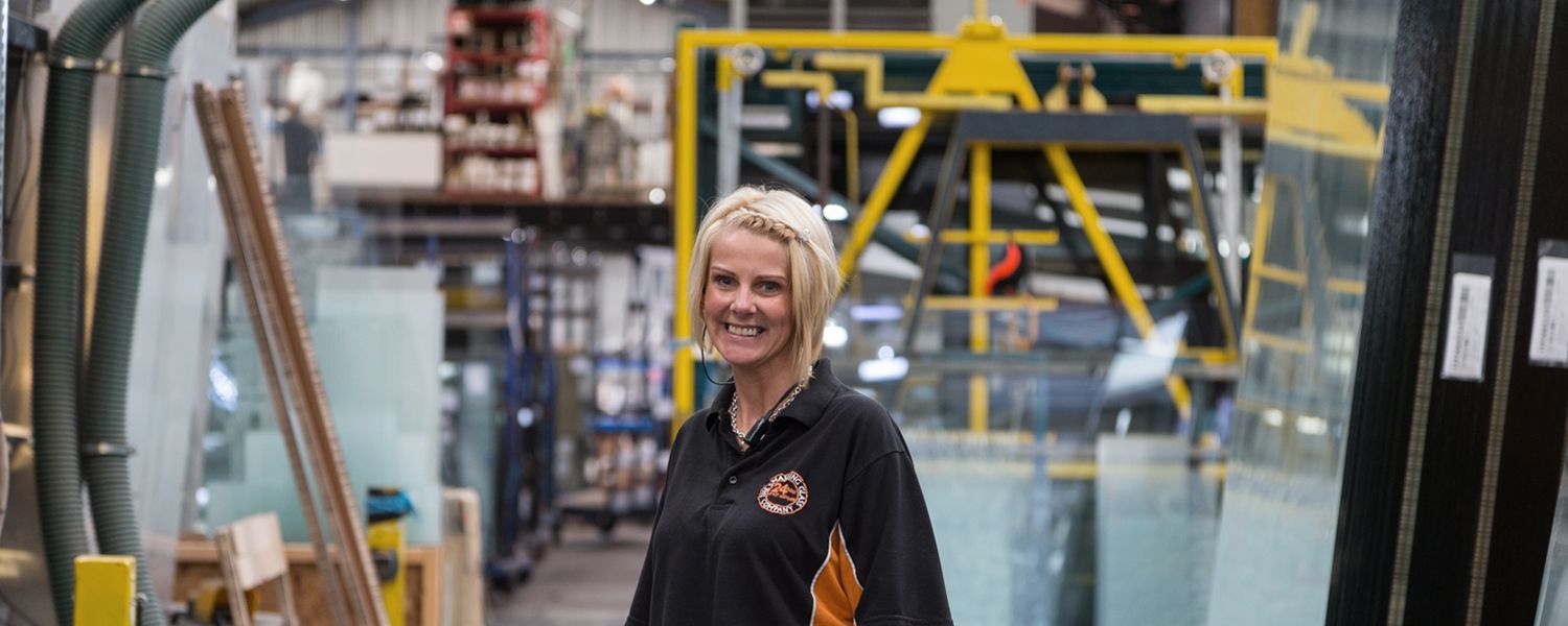 Manufacturers insurance: A smiling woman standing inside a warehouse.