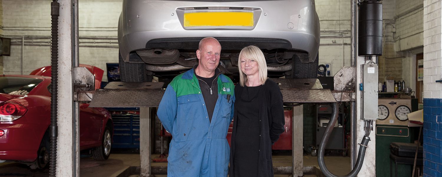 Motor trade insurance: A woman standing with a mechnaic in his workshop. 