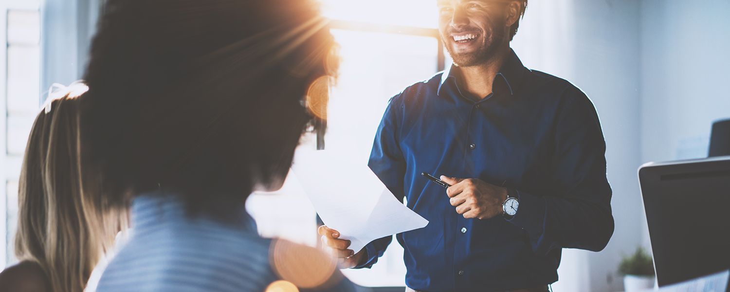 Professional indemnity: A man smiling with two women while holding a pen and paper.