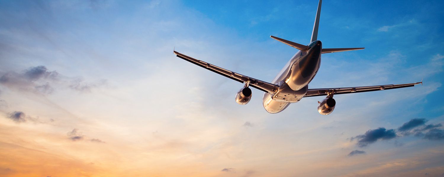 Travel insurance: A plane flying in the sky at sunset.