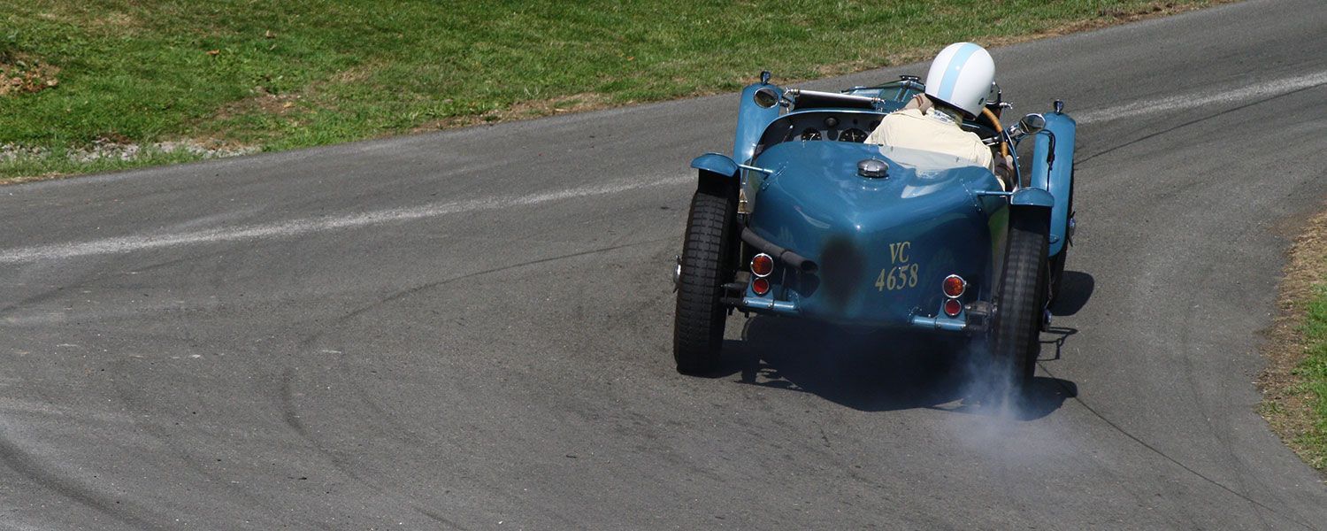 VSCC on track insurance: A driver making a turn within a blue vintage sports car. 